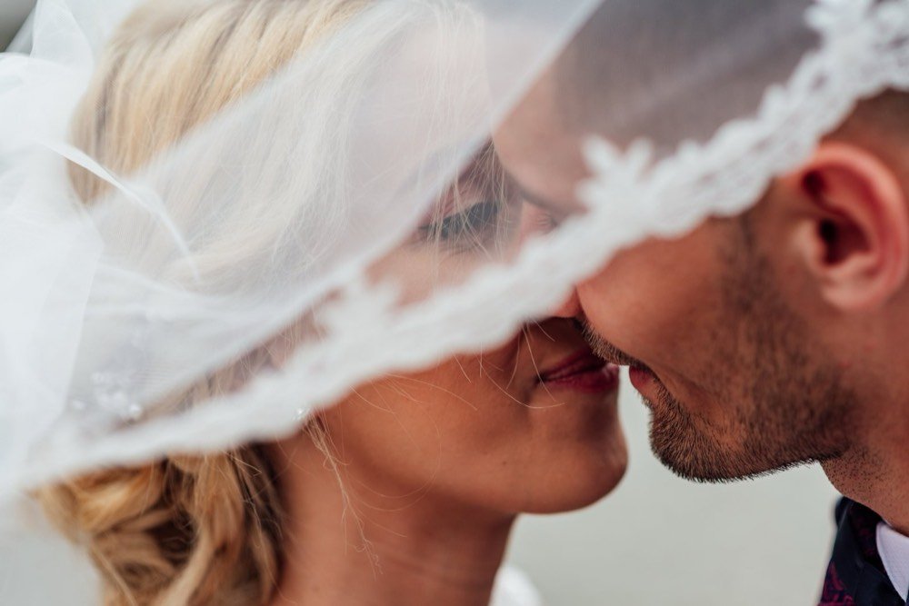 Couple sharing a kiss under a lace veil
