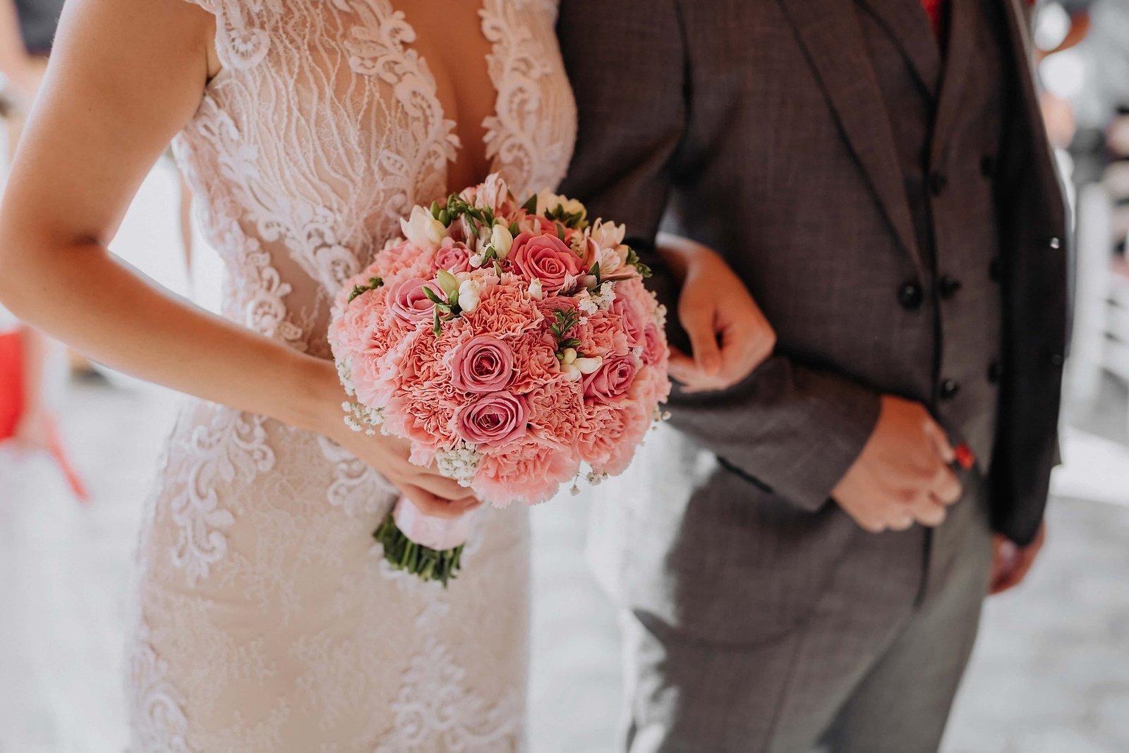 Bride holding a pink rose bouquet beside the groom